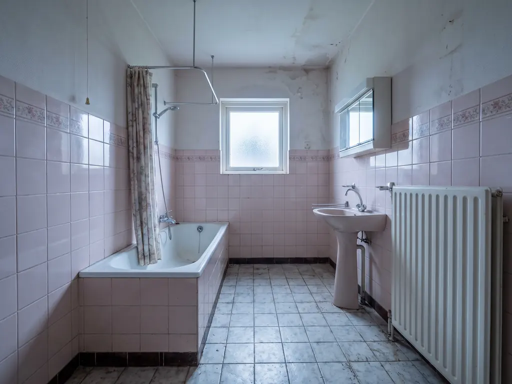 Gedateerde badkamer in Terneuzen met roze wandtegels, bad en wastafel, vóór het sloopwerk